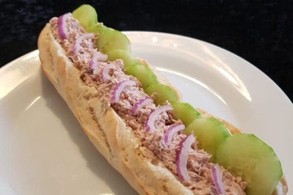 Freshly made tuna mayo baguette with crisp cucumber and red onion, perfect for a light and delicious meal.